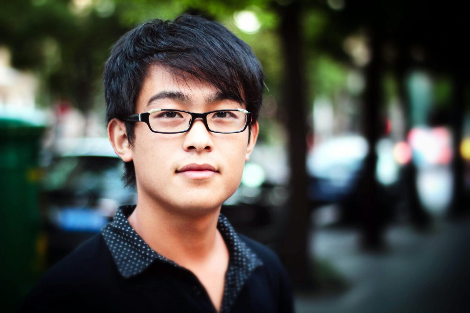 Young man standing on a street in Shanghai with a blurred background.